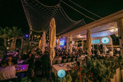 a group of people sitting at tables in front of a restaurant at חופים מול הים in Bat Yam