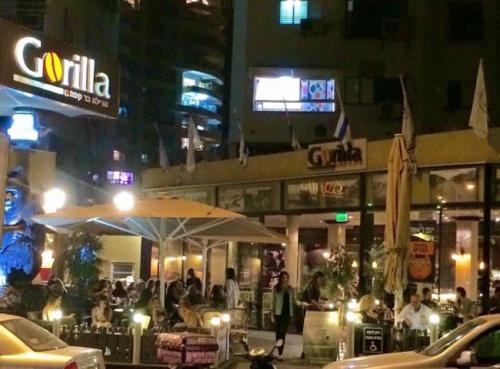a group of people standing outside a restaurant at night at Motel Hofim in Bat Yam