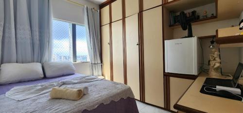 a bedroom with a bed with a desk and a window at Apartamento Vitória Vista ao Mar in Salvador