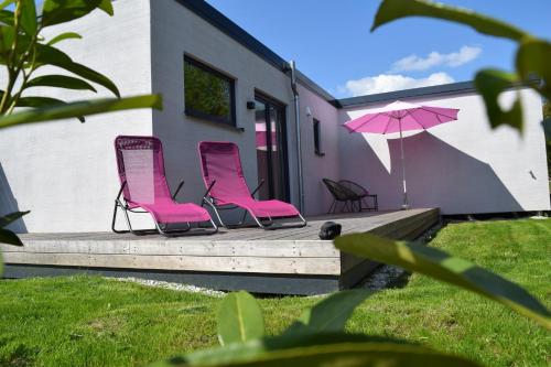 two pink chairs and an umbrella on a deck at Naturgeflüster Chalet in Morbach