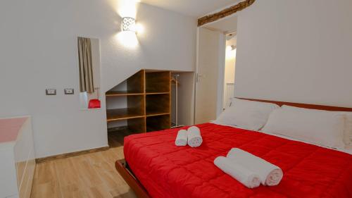 a bedroom with a red bed with white towels on it at Villa Maria in Mamoiada