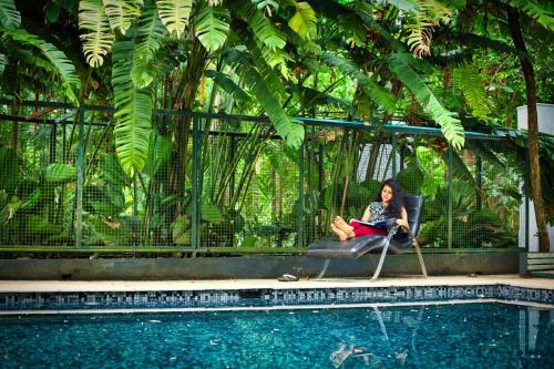 a woman sitting in a chair next to a pool at Softouch Ayurveda Village Kerala in Kizhake Chālakudi