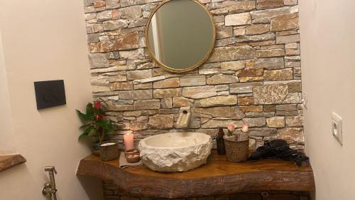 a bathroom sink with a mirror and a stone wall at Love Space Sensory Spa & relax suite in Santa Maria delle Mole