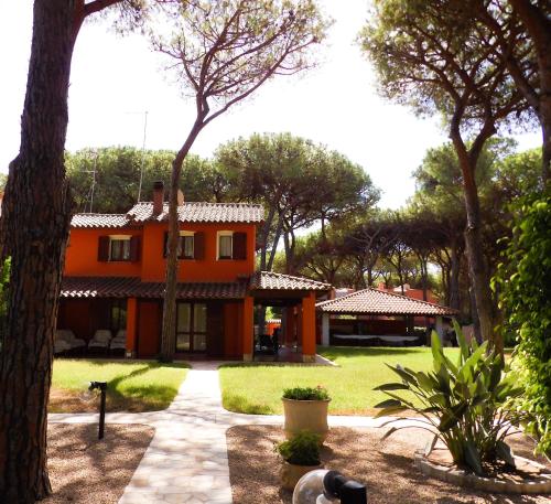 uma casa laranja com árvores em frente em Le Due Tortore Home Holiday - Villa con splendido giardino ad un minuto a piedi dal mare em Fort Village