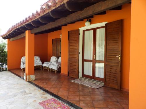 an orange house with a patio and a door at Le Due Tortore Home Holiday - Villa con splendido giardino ad un minuto a piedi dal mare in Forte Village