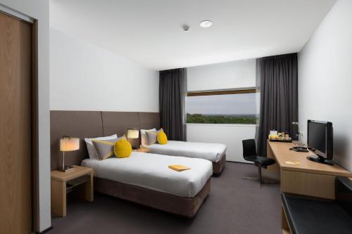 Una habitación de hotel con dos camas y un televisor. en Atura Dandenong, en Dandenong