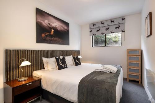 a bedroom with a bed and a window with a deer on the wall at Lantern 1 bedroom terrace with mountain views in Thredbo