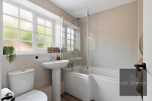 a bathroom with a sink and a toilet and a tub at 11 Friernhay Court in Exeter