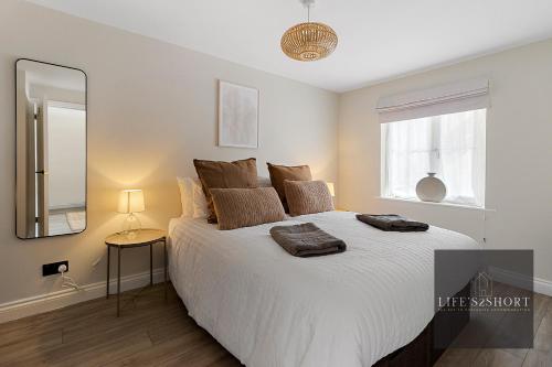 a bedroom with a large white bed with a mirror at 11 Friernhay Court in Exeter