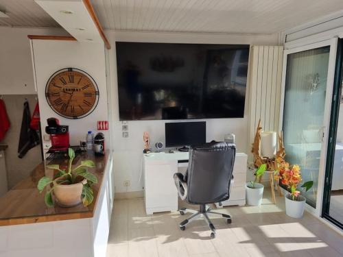 een kantoor met een bureau, een stoel en een klok bij Superbe Appartement Avec Magnifique Vue sur La mer in Saint-Cyprien