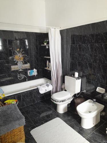 a black tiled bathroom with a toilet and a bath tub at Art House Syros in Ermoupoli