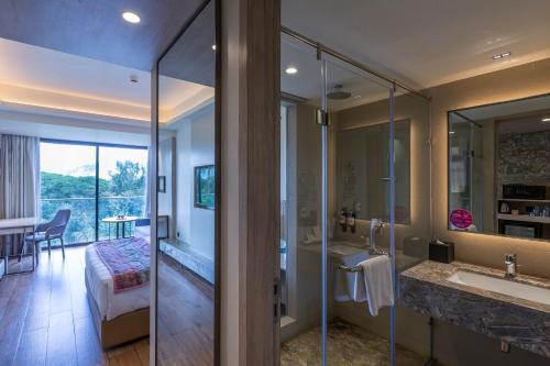 uma casa de banho com um chuveiro e um lavatório e um quarto em Regenta SGS Greenotel - Lonavala em Lonavala