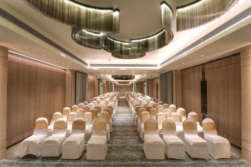 a row of chairs in a room with a long aisle at Regenta SGS Greenotel - Lonavala in Lonavala