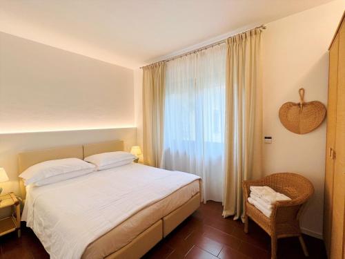 1 dormitorio con cama, ventana y silla en Villa Phoenix - Lake Apartments, en Riva del Garda
