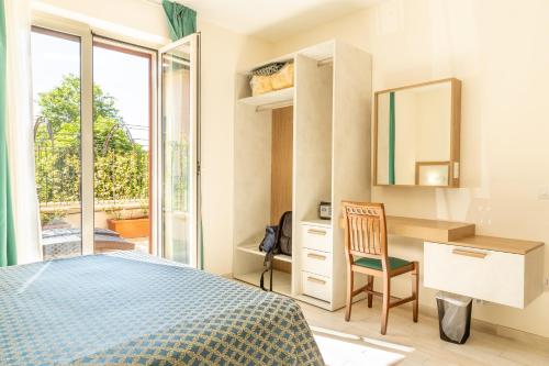 1 dormitorio con cama, escritorio y espejo en Verde Coccola - Casa Vacanze, en Ospedaletto dʼAlpinolo