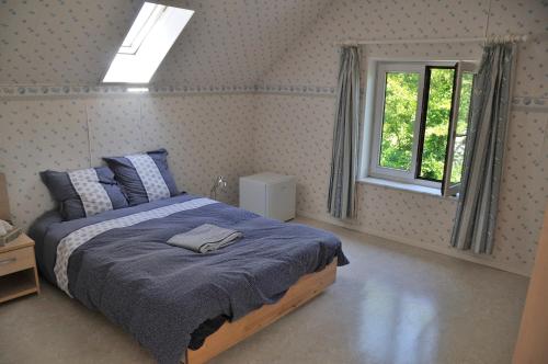 ein Schlafzimmer mit einem Bett mit einer blauen Decke und einem Fenster in der Unterkunft Suite familiale avec 2 Chambres dans une villa - quartier vert et boisé - 5 kms de Namur in Namur