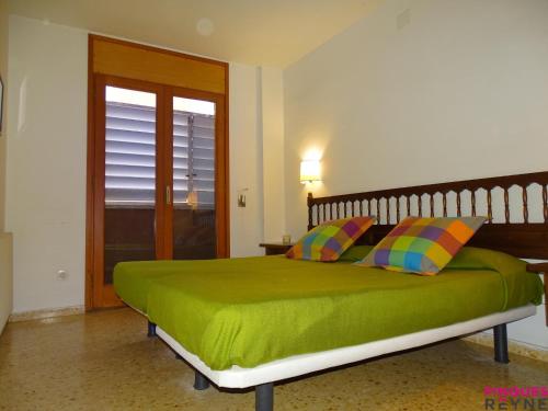 a bedroom with a green bed with two colorful pillows at BAHIA esc B 5º2ª in Sant Feliu de Guíxols