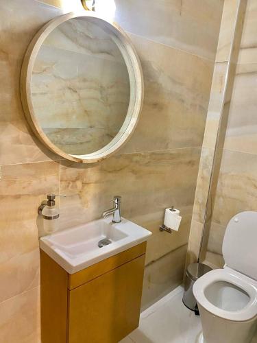 La salle de bains est pourvue d'un lavabo, d'un miroir et de toilettes. dans l'établissement Eleusis luxury flat, à Elefsina