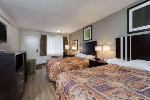 a hotel room with two beds and a television at Days Inn by Wyndham Harrisburg North in Harrisburg