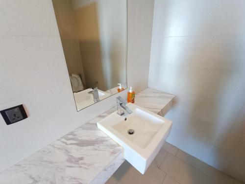 a white bathroom with a sink and a mirror at Straits Residence Melaka Private Suites in Melaka