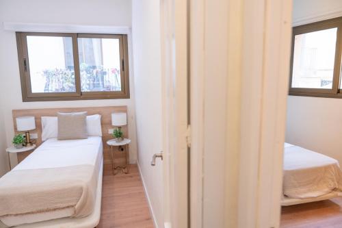 a small room with two beds and two windows at Rambla de Mar Apartments in Barcelona