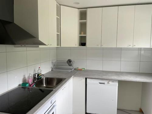 a kitchen with white cabinets and a sink at 3 bedroom lakehouse with private bridge and garden in Sundsvall