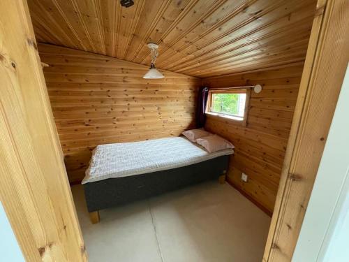 a small room with a bed in a wooden cabin at 3 bedroom lakehouse with private bridge and garden in Sundsvall