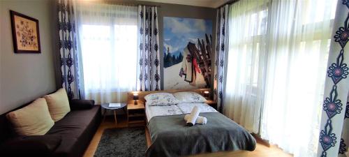 ザコパネにあるHosana Zakopane Pokoje Gościnne i Apartamentyのベッド1台とソファが備わる小さな客室です。