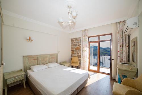 a bedroom with a white bed and a balcony at Yakamoz Hotel Gökçeada in Gokceada Town