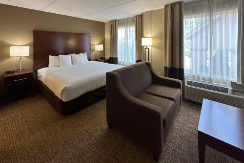 Habitación de hotel con cama y silla en Comfort Suites Airport en Charlotte