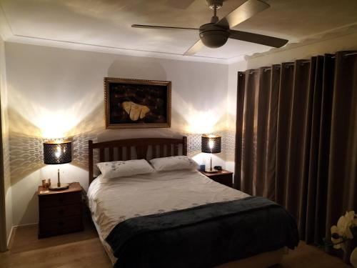 een slaapkamer met een bed, een plafondventilator en 2 lampen bij Mountain View Beach House in Catalina