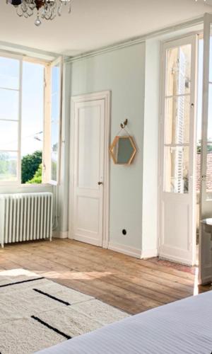 une chambre avec une porte et des fenêtres blanches dans l'établissement Les Tourelles, à Saint-Christoly-Médoc