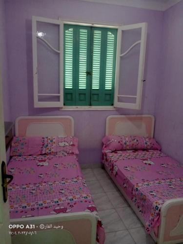 2 bedden in een kamer met groene luiken bij رأس البر in Ras El Bar