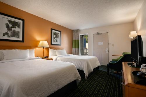 a hotel room with two beds and a flat screen tv at Days Inn by Wyndham Chattanooga/Hamilton Place in Chattanooga
