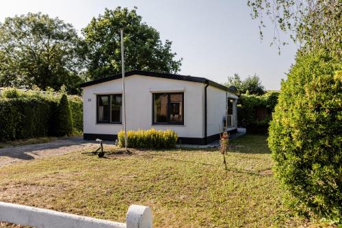 a small white house in a yard at Familie bungalow op vakantiepark bij zee in Baarland