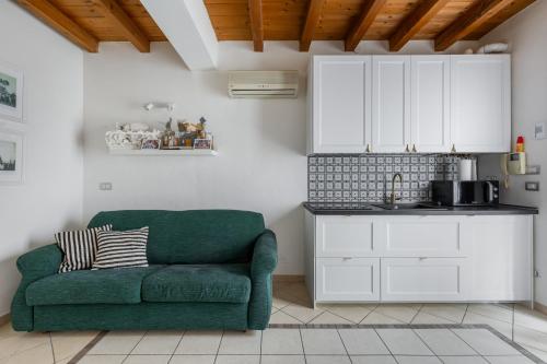 a living room with a green couch and a kitchen at Osvaldo - parcheggio e giardino privato in San Giovanni in Persiceto