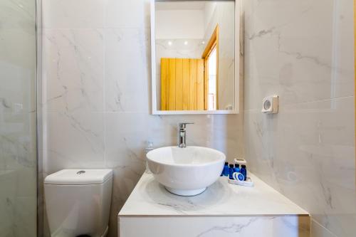 a bathroom with a sink and a mirror and a toilet at Ostria Caldera Studios in Oia