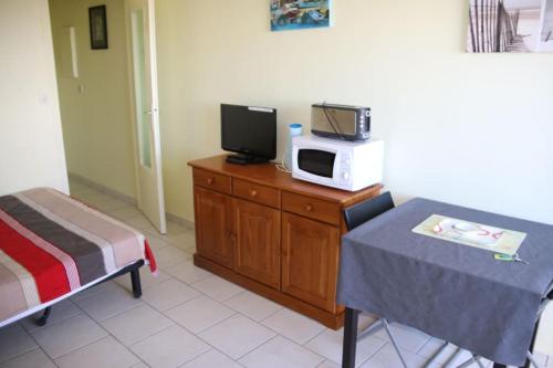 Cette chambre comprend un lit, une télévision et une table. dans l'établissement Studio 340, Héliopolis AB au village naturiste, au Cap d'Agde