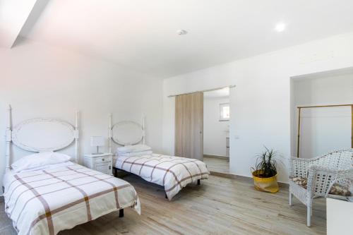a white bedroom with two beds and a mirror at Villa Principezinho in Portimão