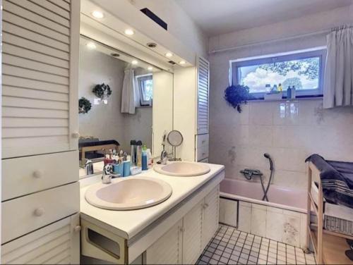 ein Badezimmer mit zwei Waschbecken, einer Badewanne und einem Spiegel in der Unterkunft Suite familiale avec 2 Chambres dans une villa - quartier vert et boisé - 5 kms de Namur in Namur