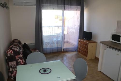 een woonkamer met een tafel en stoelen en een magnetron bij Studio 141 Port Soleil B1 au village naturiste in Cap d'Agde