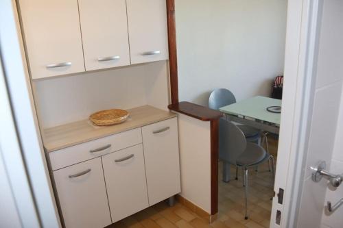 een keuken met witte kasten en een tafel en stoelen bij Studio 141 Port Soleil B1 au village naturiste in Cap d'Agde