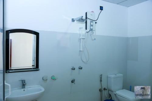 a bathroom with a shower and a toilet and a sink at Jayananda Estate Villa in Dickwella