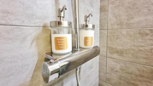 Deux bouteilles d'odorisants sur une étagère métallique dans une salle de bains dans l'établissement Chez Margot & Fawaz - Parking - 3 chambres - Jardin - Relax BNB, à Colmar