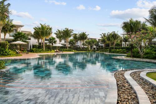 a swimming pool at a resort with palm trees at Angsana Ho Tram in Ho Tram