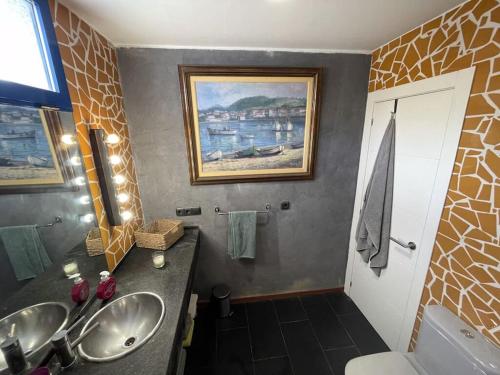 uma casa de banho com dois lavatórios e uma pintura na parede em Magnifico chalet con piscina em Vallesa de Mandor