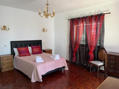 een slaapkamer met een bed met rode kussens en een raam bij Vivenda Marias in Lagoa