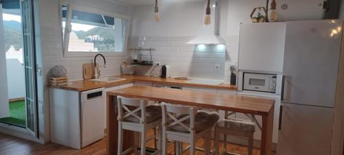 a kitchen with a wooden table and a white refrigerator at Apartamento burbujas playa in El Pozo del Esparto