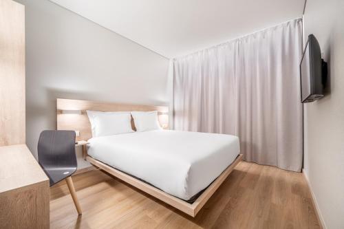 a bedroom with a white bed and a tv at Moov Hotel Lisboa Oriente in Lisbon