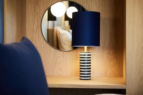 a lamp sitting on a shelf with a mirror at Kirk Suites in Vejle